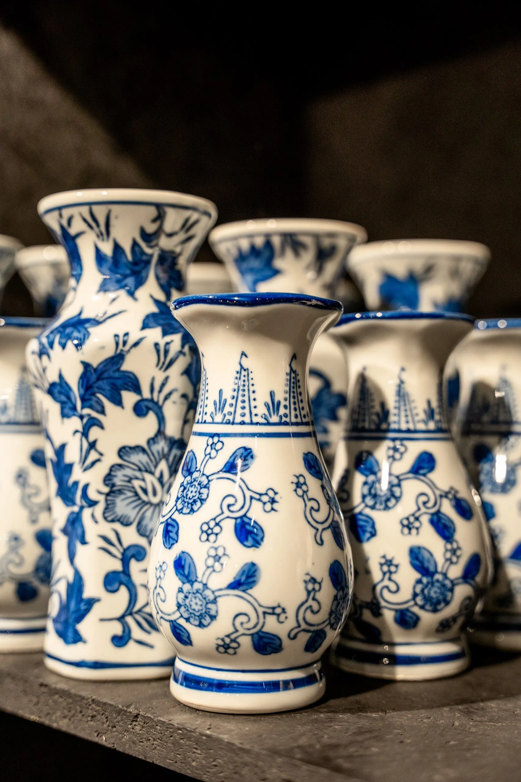 Blauw-witte vazen met bloemmotieven, dicht op elkaar op een donkere plank